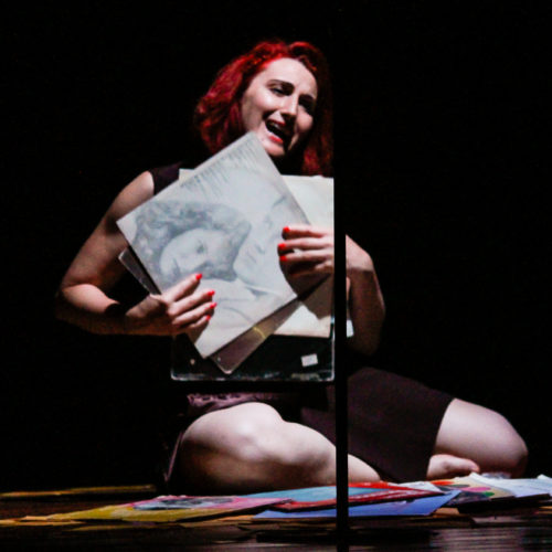 Atriz Mari Feil segurando um disco de vinil em cena da peça A Rainha do Rádio